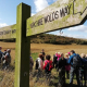 Wooden sign with walkers in the background.